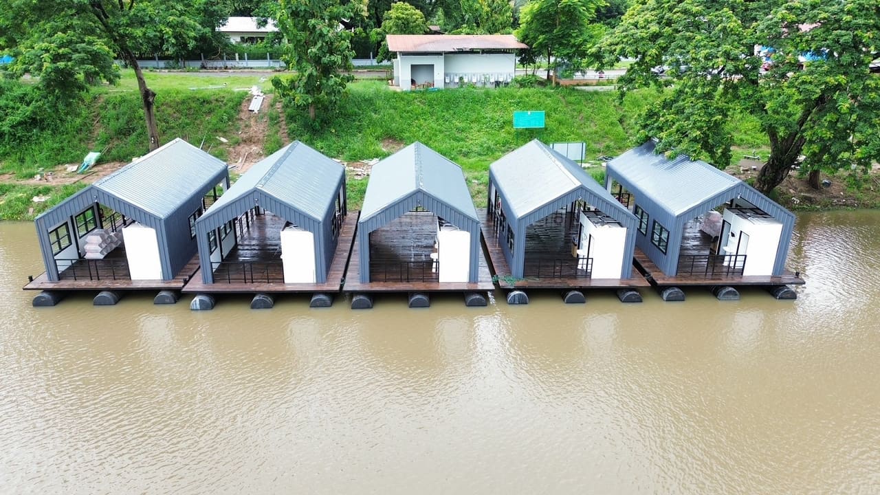 แพที่พักหลังคาจั่ว 5 หลังจอดเรียงริมฝั่ง มองจากด้านหน้า — แพที่พักล่องในลำน้ำ เขื่อน แม่น้ำ T.K.M. Aquatic